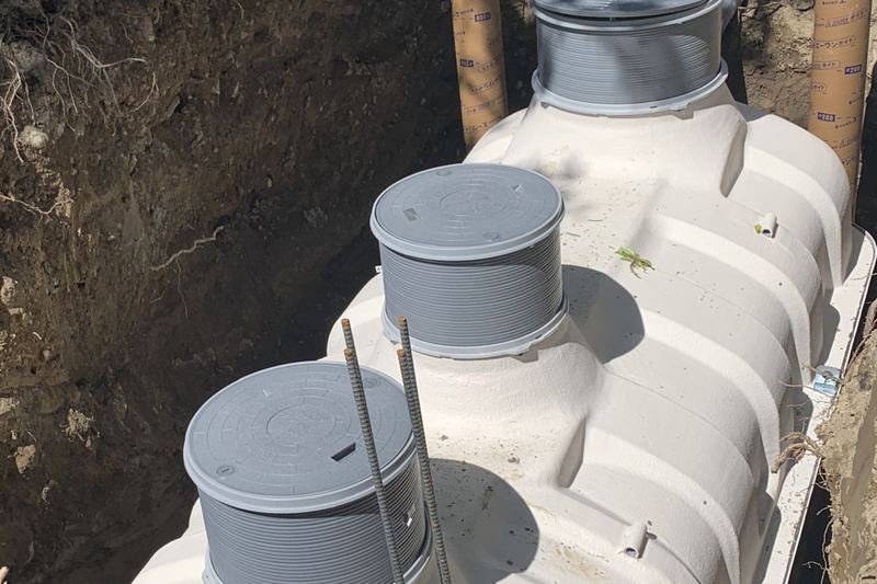 Packaged treatment tank with access risers being installed in an excavation